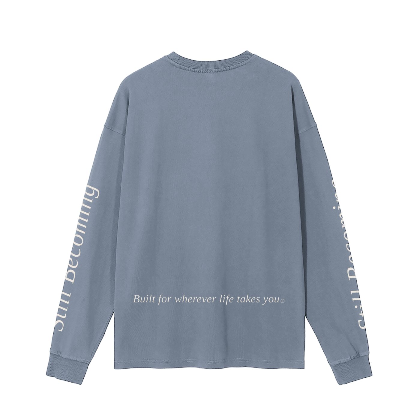 The Gatlinburg Long Sleeve T-Shirt is a blue unisex cotton tee shown from the back, featuring white text on the sleeves and lower back. The back says "Built for wherever life takes you" and the sleeves read "Still Becoming"—ideal for street casual style.