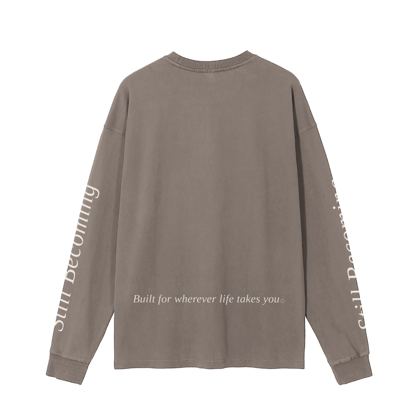 The Gatlinburg Long Sleeve T-Shirt is a street-casual, taupe top with “Built for wherever life takes you” on the lower back and “Still Becoming” in light serif lettering down both sleeves.