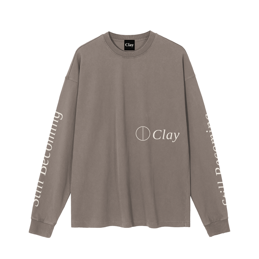 The Gatlinburg Long Sleeve T-Shirt is a unisex taupe cotton sweatshirt with Clay and a circular logo on the front, plus “Still Becoming” in white down both sleeves—a street casual essential.