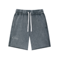 Pensacola Shorts: Gray washed unisex cotton shorts with a loose mid waist, elastic waistband, white drawstrings, and "Clay" printed in white on the left leg. Vintage streetwear style, shown laid flat on a white background.