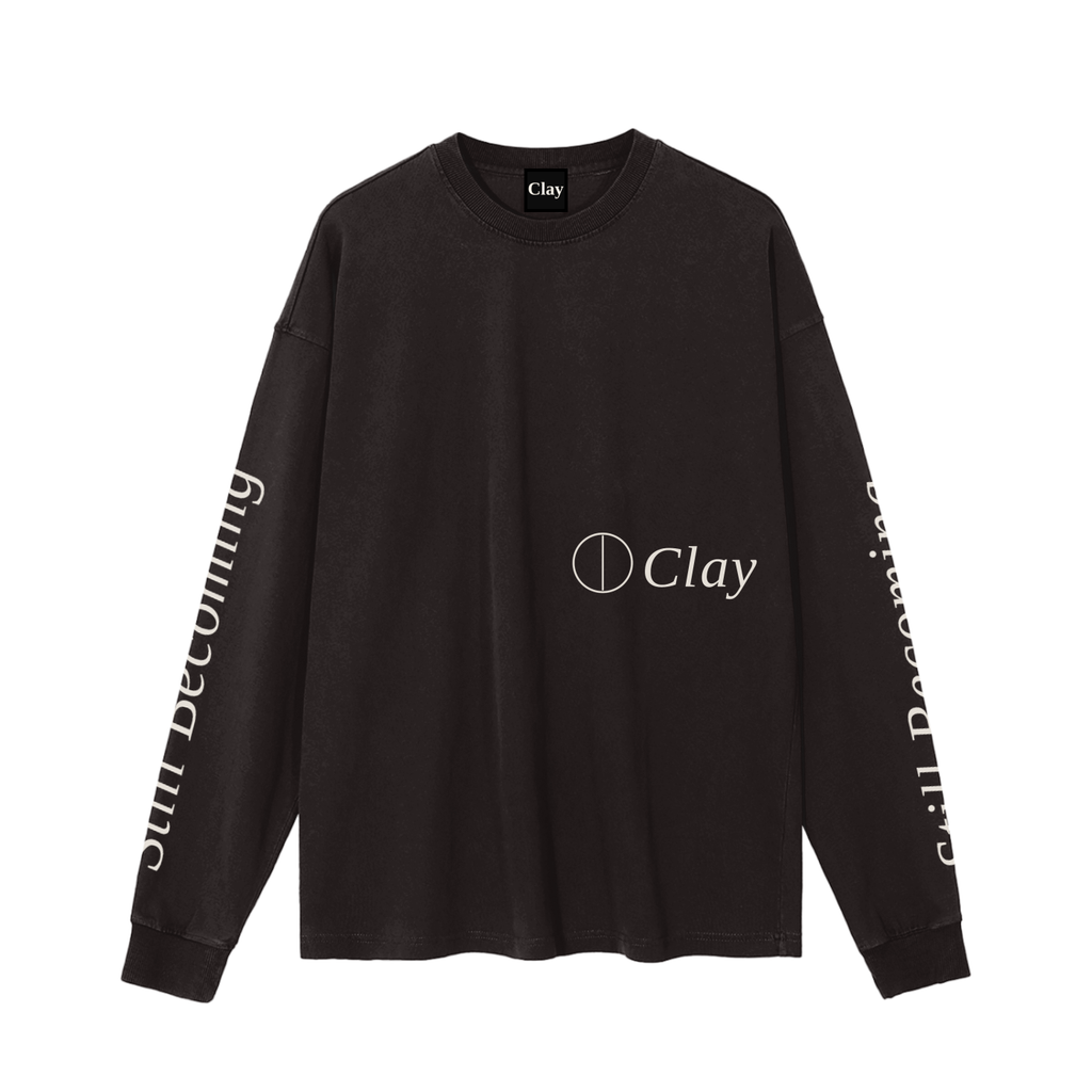 The Gatlinburg Long Sleeve T-Shirt is a black unisex cotton top featuring the Clay logo and circle graphic on the front, plus Still Becoming text on the sleeves. A stylish streetwear pick for your autumn winter wardrobe.