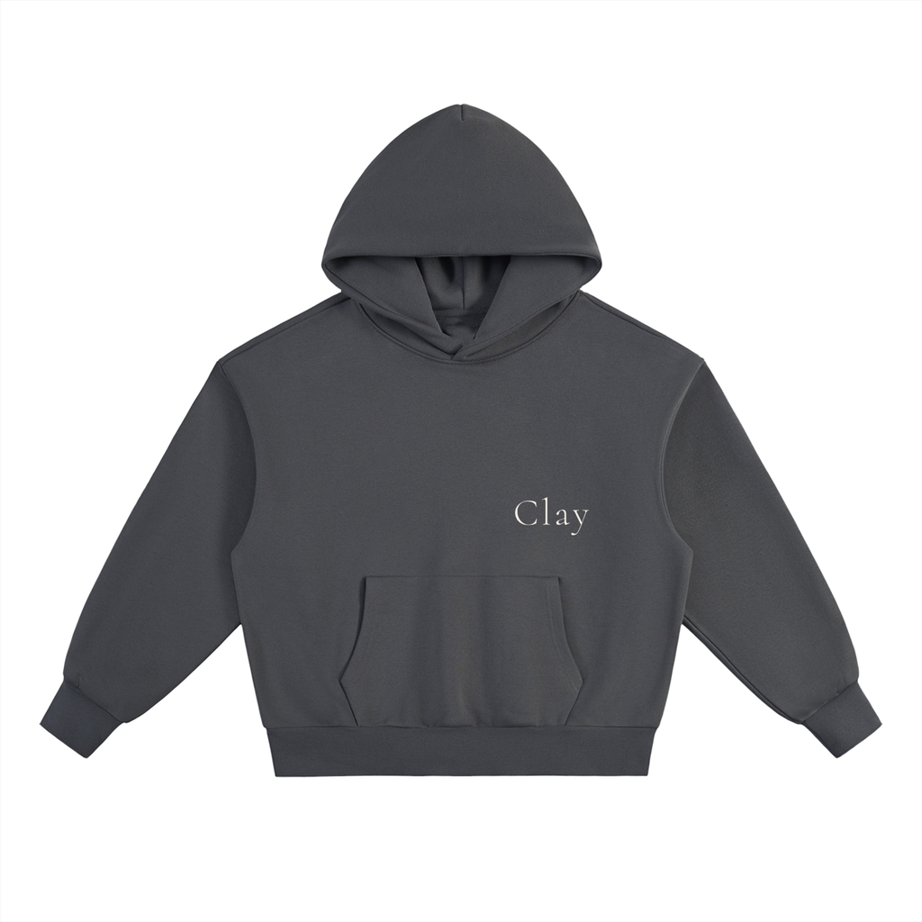 The Selma Hoodie is a dark gray, oversized unisex hoodie with long sleeves, a front pocket, and "Clay" in white on the upper left chest. Made from a comfy cotton blend for everyday wear.